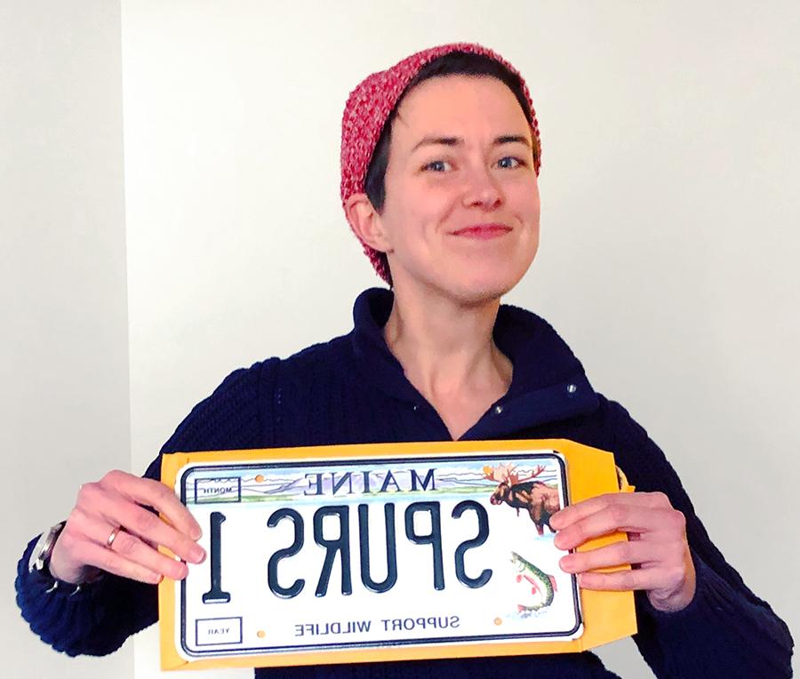 Janie is holding a Maine license plate that says "SPURS 1"